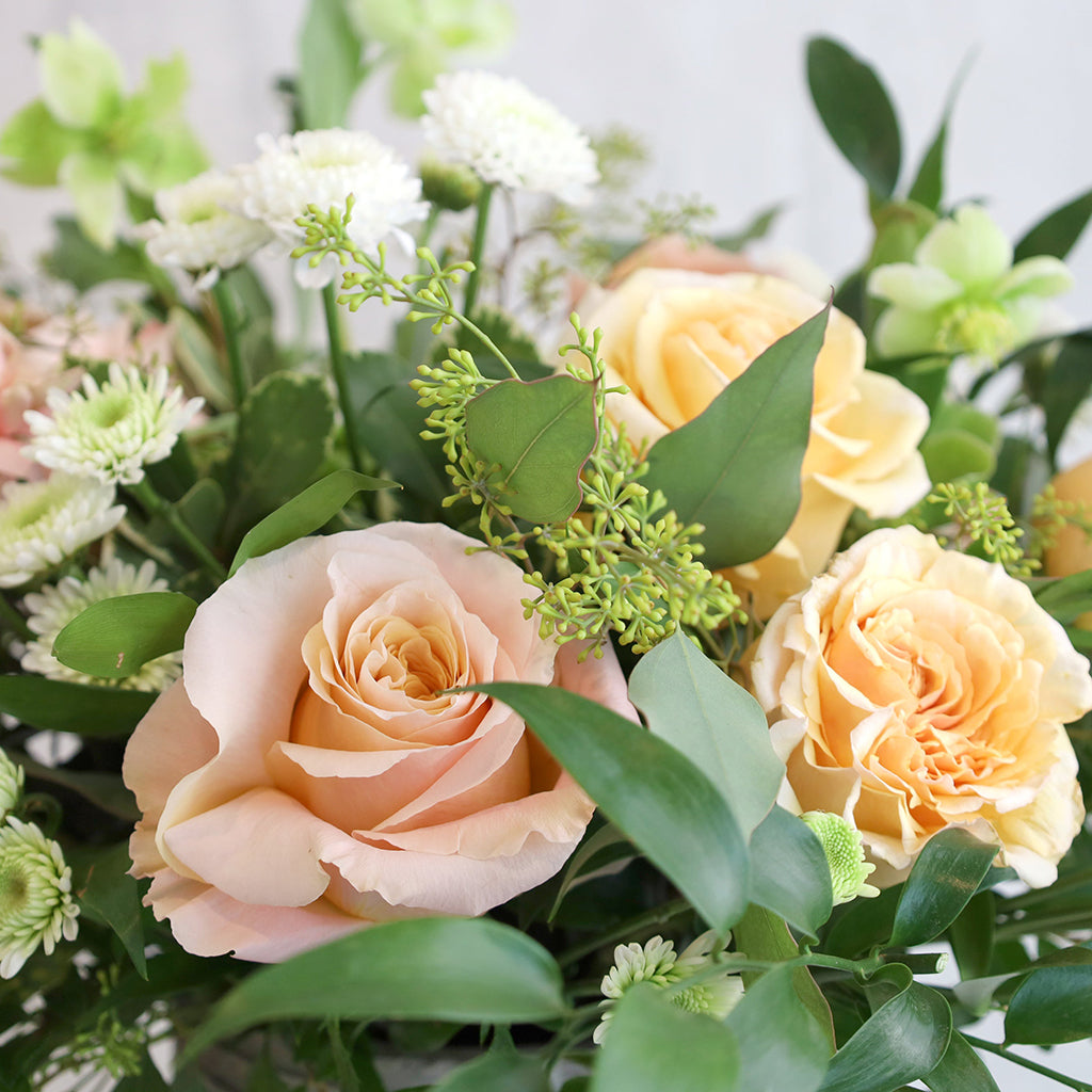 Bouquet of Pearl Roses, Shimmer Roses, Carnations, Hellebores, and White Pompoms with Seeded Eucalyptus and Ruscus greeneries.